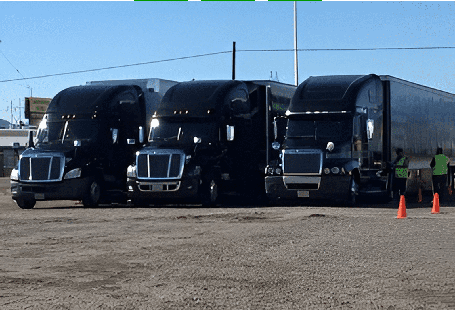 Black trucks lined up with orange cones